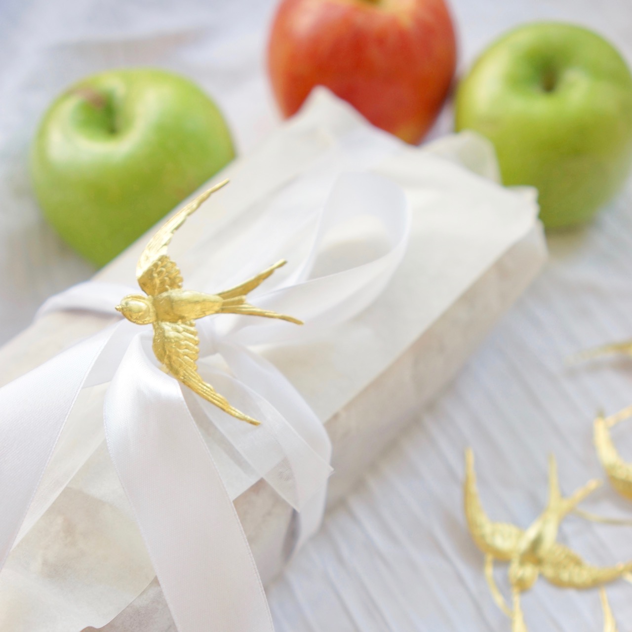 עוגת תפוחים מקמח כוסמין עטופה בנייר לבן וסרט בד. גבישס. מתכונים לראש השנה.
